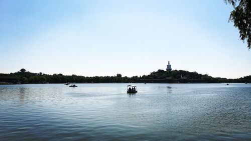 Boats in calm lake against clear sky