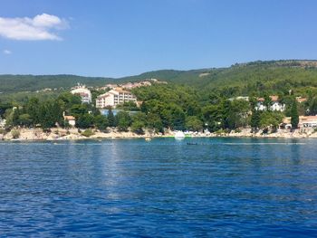 Scenic view of townscape by sea against blue sky