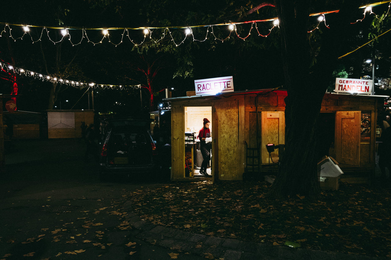 PEOPLE STANDING ON ILLUMINATED STREET DURING AUTUMN