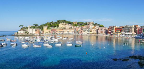 Aerial view of townscape by sea against clear blue sky