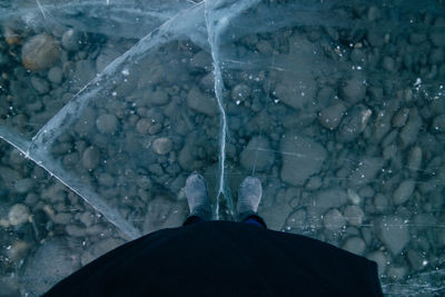 View of rubber boots on frozen lake over stone