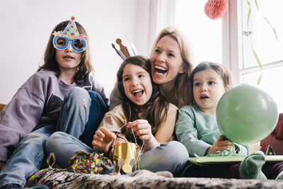 Cheerful mother with children enjoying birthday party at home