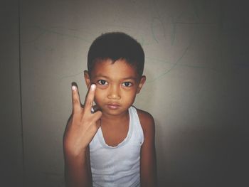 Portrait of cute boy standing against wall