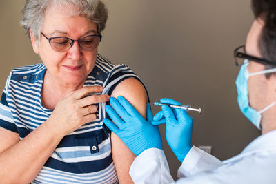 Older woman getting injected with a vaccine by doctor in upper arm.