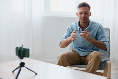 Portrait of man using mobile phone while sitting on table