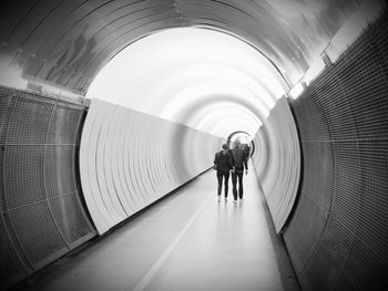 Rear view of couple walking in illuminated tunnel