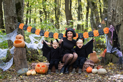 Halloween. mother with two little sons twins in halloween costumes having fun outdoor