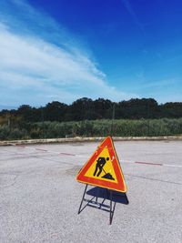 Arrow sign on road against sky