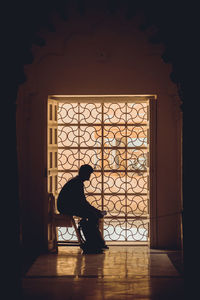 Side view of silhouette man sitting outside building