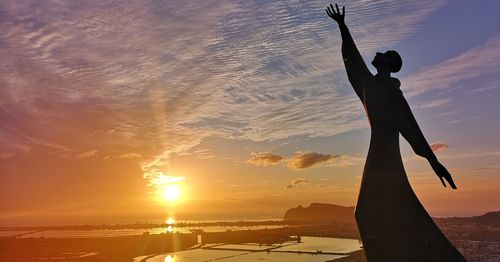 Silhouette person standing on beach against sky during sunset