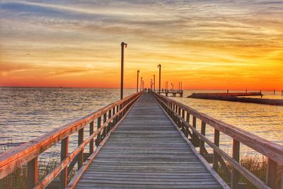 Pier over sea against sky during sunset