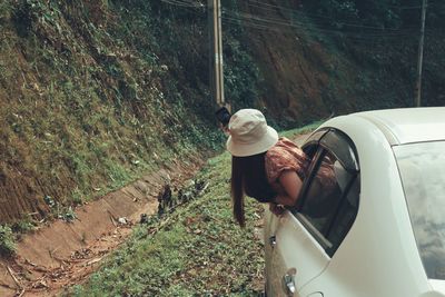 Side view of woman taking selfie while leaning out from car window