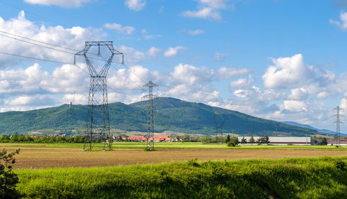 Electricity pylon on field against sky