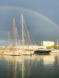 Serene view of three boats in harbor under a rainbow