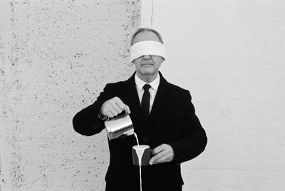 Low section of man standing against wall with a cup of a milk 