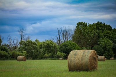 Hay bales on field against sky