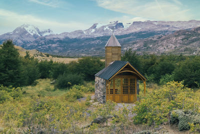 Built structure by trees and mountains against sky