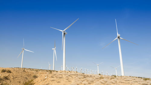 Windmill on field against clear blue sky