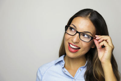 Close-up of cheerful young woman wearing eyeglasses against white background