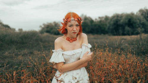 Portrait of young woman standing on field