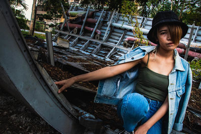 Portrait of young woman looking away standing against metal structure