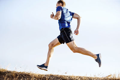 Low angle view of woman exercising against clear sky