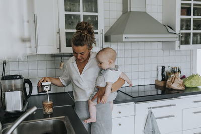 Mother with baby making coffee at home