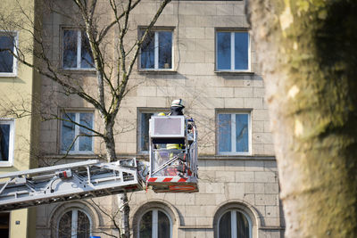 Man standing in cherry picker against building