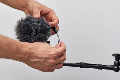 Cropped hand of woman holding figurine against white background