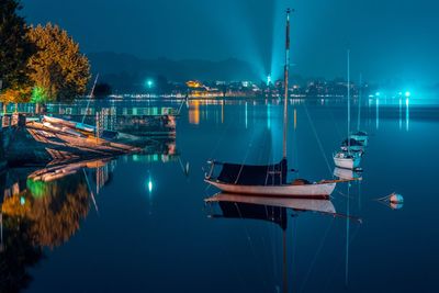 Sailboats moored on lake against sky at night