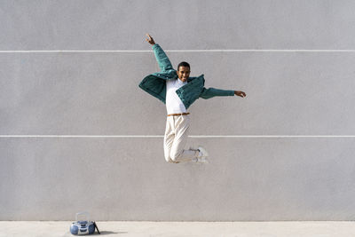 Full length of man jumping against wall