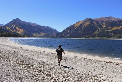 Rear view of man on shore against sky