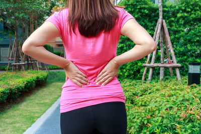 Rear view of woman with backache standing against plants