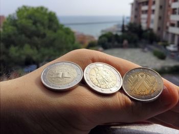 Close-up of coins on hand against beach