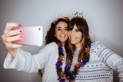 Portrait of smiling women doing selfie against gray backgrounds
