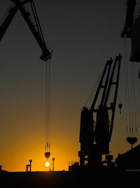 Silhouette crane against sky during sunset