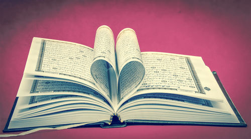 Close-up of heart shape on book against pink background