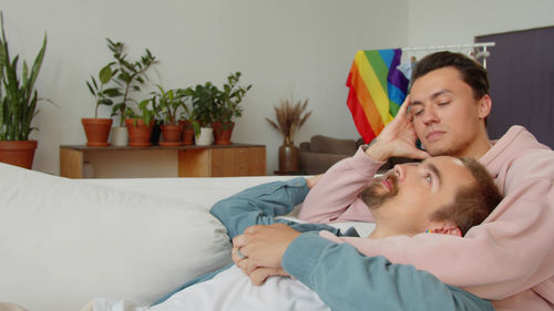 Gay couple embracing while sitting on sofa