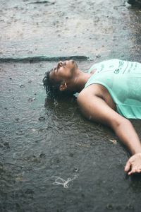 High angle view of man lying on road during rainy season