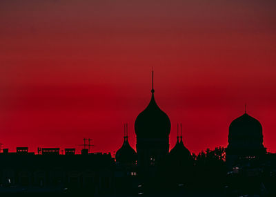 Silhouette of temple against buildings during sunset