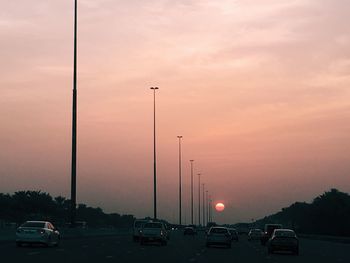 Cars on road against sky during sunset