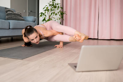 Female practicing arm balance. yoga class live streaming concept. woman doing eight-angle pose 