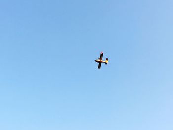 Low angle view of airplane against clear blue sky