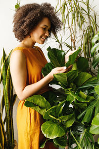 Young woman looking away while standing in plant