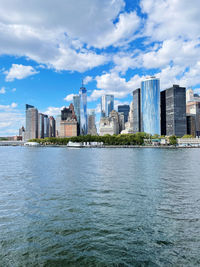 Buildings by river against sky in city