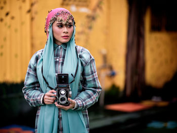 Beautiful asian female posing with a retro camera