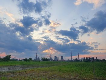 Smoke emitting from chimney on field against sky during sunset