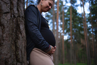 Portrait of young woman standing against trees