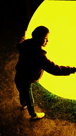 Side view of silhouette boy on field during sunset