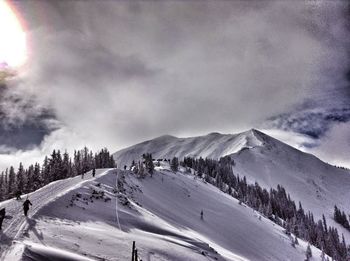 Scenic view of snow covered mountains against cloudy sky